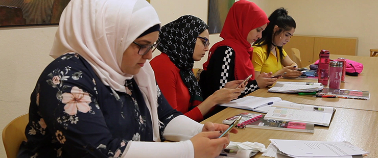 Vier Frauen lernen mit Smartphones an einem Tisch mit Bchern und Heften. Foto: Bildungsfilm